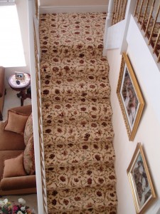 Top view of a carpeted staircase with patterned runner and framed pictures on the wall.