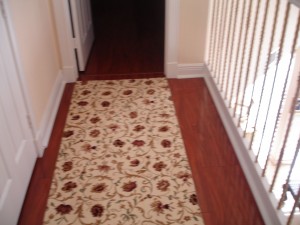 Floral patterned runner rug on wooden floor in a hallway.