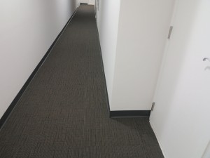 A long, empty hallway with carpeted floor and white walls.