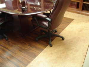 An office chair on a wooden and carpeted floor near a conference table.
