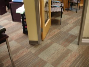 Carpeted floor with a yellow door and furniture in the background.