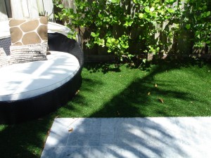 Sunlit garden corner with lush greenery and a cozy round chair.