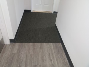 Transition from wooden floor to dark carpet in a hallway.