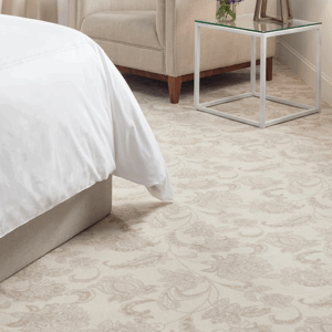 Elegant beige floral carpet next to a bed and side table.